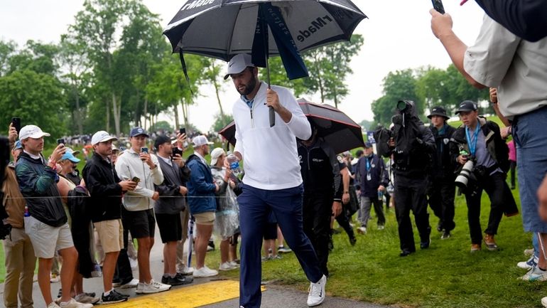 Scottie Scheffler walks to the tee on the 11th hole...