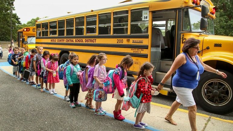 A staffer leads kindergartners into the Unity Drive Pre-Kindergarten and...