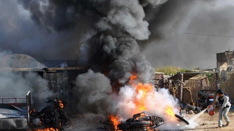 A Palestinian tries to extinguish a fire after an Israeli...