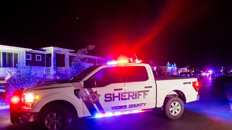 A police vehicle remains stationed at a scene where four...