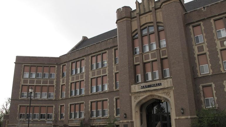 People walk past May Hall, the main administrative building at...