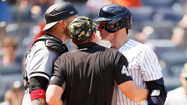 Uumpire Nick Mahrley attempts to separate Yasmani Grandal of the White Sox...