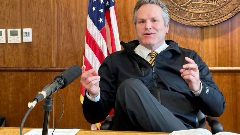 Alaska Gov. Mike Dunleavy gestures while speaking with reporters on...