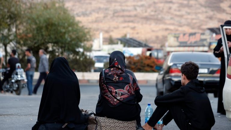 Lebanese fleeing the Israeli bombardment, sit on the ground after...