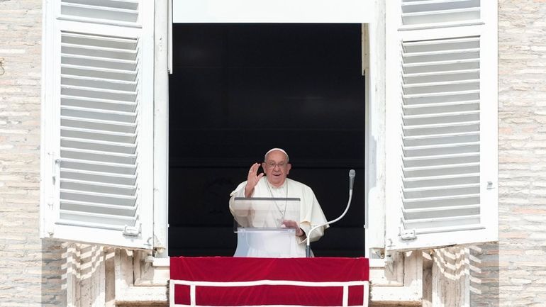 Pope Francis waves during the Angelus noon prayer from the...