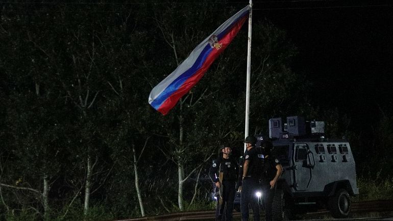 FILE -Kosovo police officers guard road near the village of...