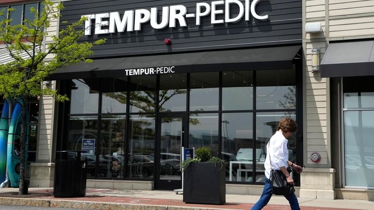 A passer-by walks near the front of a Tempur-Pedic mattress...