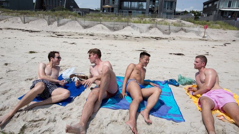 Friends sit along the beach in the Pines at Fire...