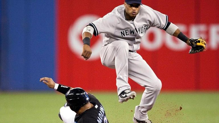 The Yankees' Robinson Cano throws to first after forcing out...