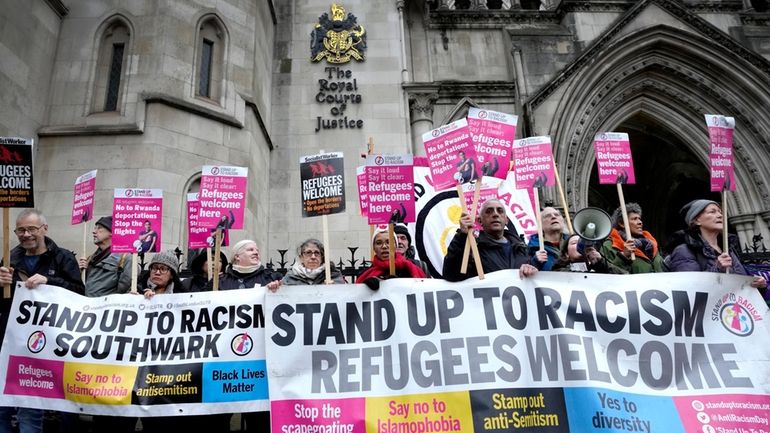 Stand Up To Racism campaigners hold banners outside the High...