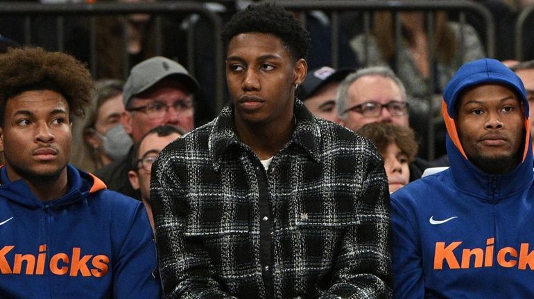 The Knicks' RJ Barrett sits on the bench in street clothes...