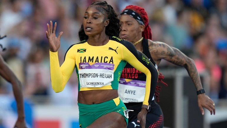 Jamaica's Elaine Thompson-Herah, center, races to win a women's 100m...