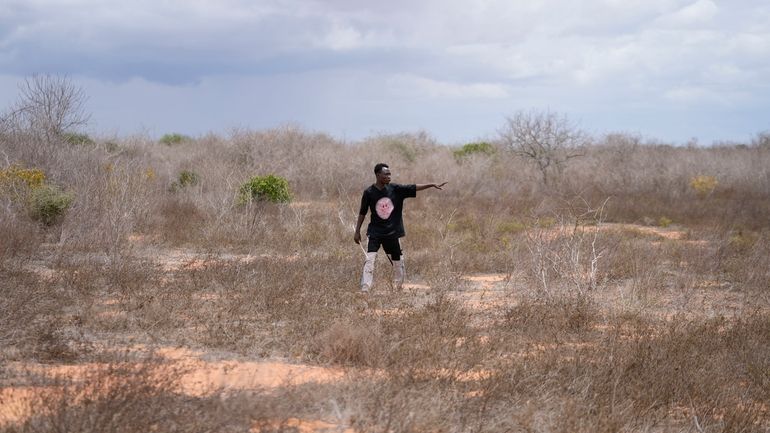 Shukran Karisa Mangi, 25, a gravedigger, walks in the bush...