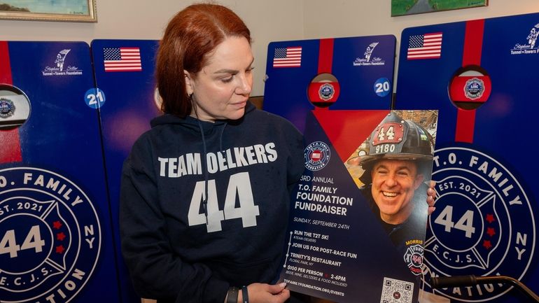 Erika Oelkers, of Floral Park, holds a poster of her late husband,...