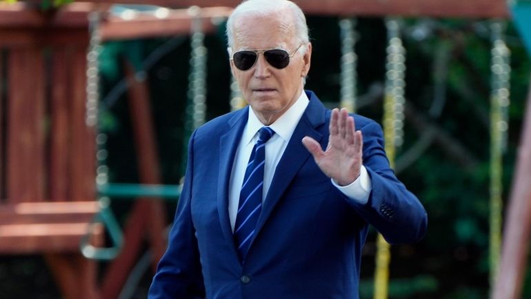 President Joe Biden waves to the media as he walks...