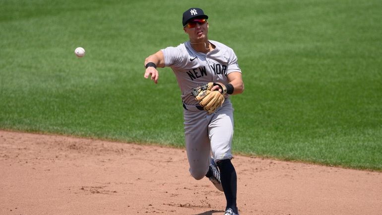 Yankees shortstop Anthony Volpe throws to first base to put...