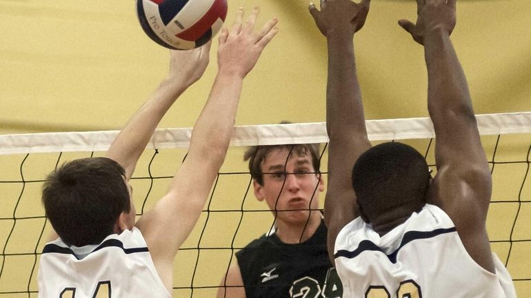 Bellmore JFK's Gary Anderson, center, spikes the ball just over...