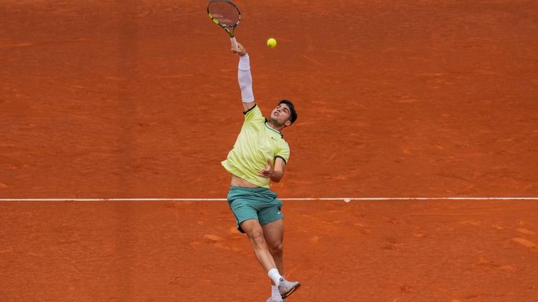 Carlos Alcaraz, of Spain, returns the ball to Thiago Seyboth...