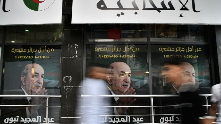 People walk past posters of Algerian President Abdelmadjid Tebboune, after...