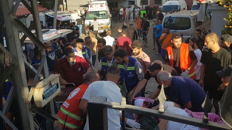 Civil Defense first-responders carry a man who was wounded after...