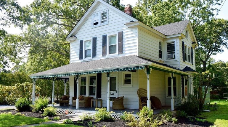 A covered front porch at the East Quogue home includes...