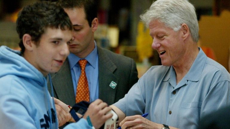 Former President Bill Clinton signs the cap of Alan Weiss,...