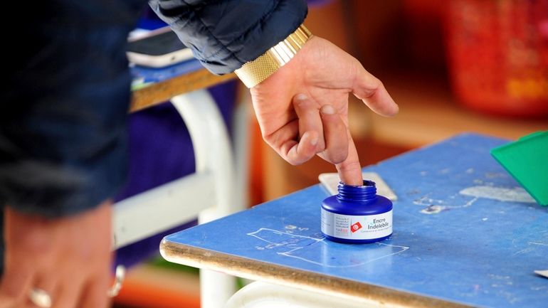 A man dips his finger in ink after casting his...