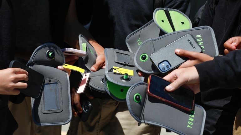 Students retrieve their cellphones after unlocking the pouch that secures...