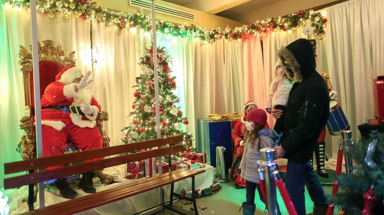 Santa greets guests from behind a plexiglass window at the Vanderbilt...