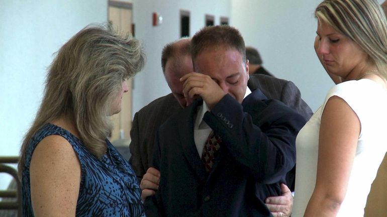 Matthew J. Byank, 21, surrounded by family members, weeps at...