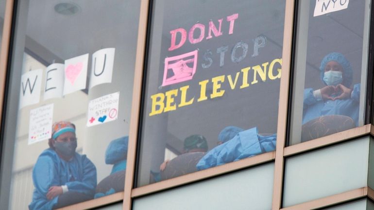 Healthcare workers at the windows of NYU Winthrop University Hospital in...