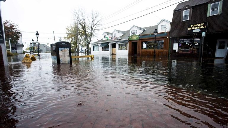 Spectators check out the flooding on Main Street in Port...