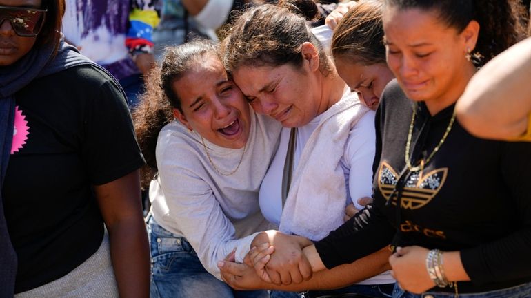 A sister of miner Santiago Mora, left, cries with other...