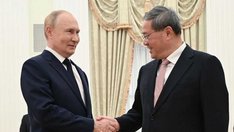 Russian President Vladimir Putin and Chinese Premier Li Qiang shake...