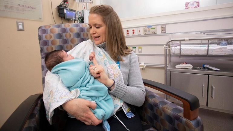 Jodi Abbinanti, of Port Jefferson Station, a cuddle volunteer, holds...