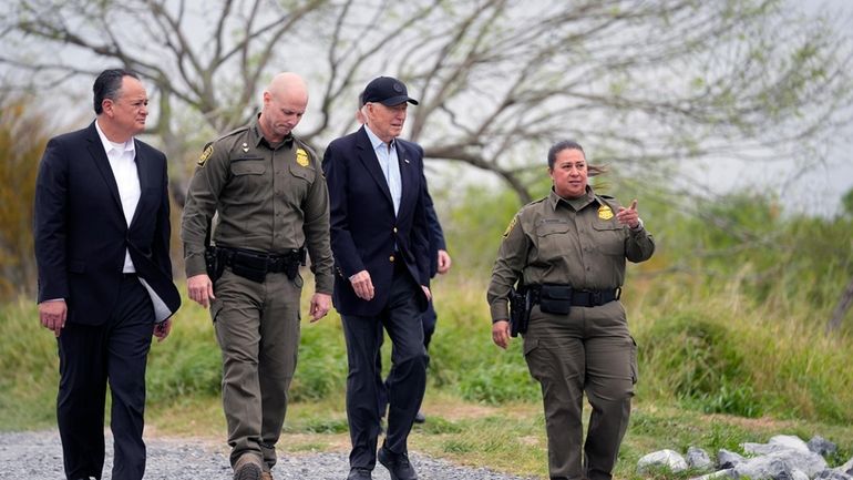 President Joe Biden, second from the right, looks over the...