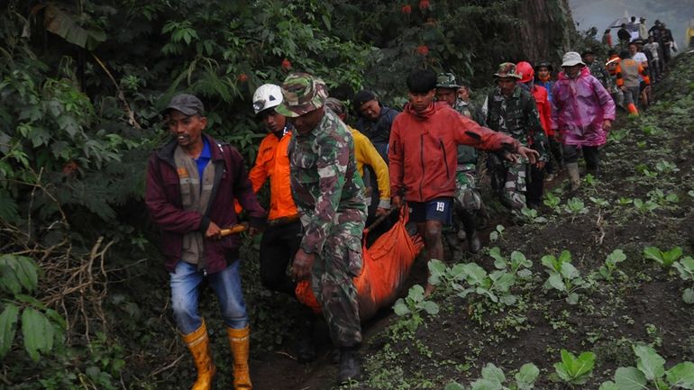 Rescuers carry the body of a victim of the eruption...