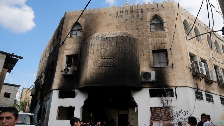 Palestinians stand outside a heavily damaged mosque following an Israeli...