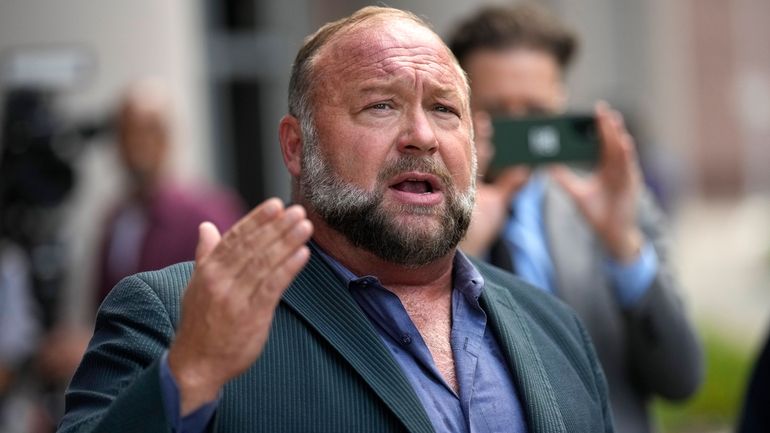 Alex Jones speaks to the media after arriving at the...