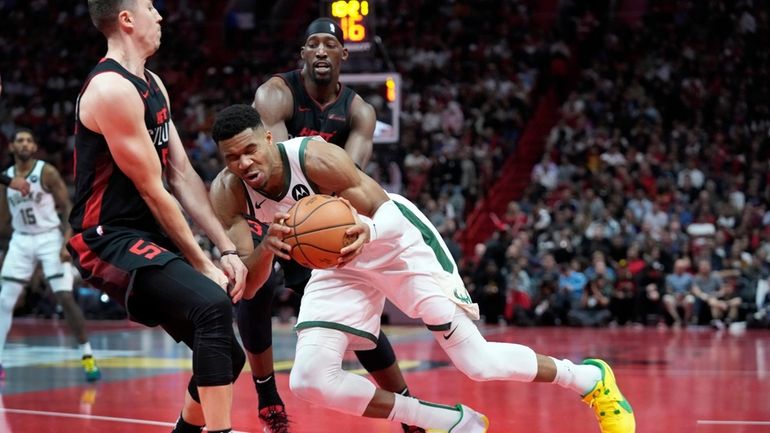 Milwaukee Bucks forward Giannis Antetokounmpo, center, collides with Miami Heat...