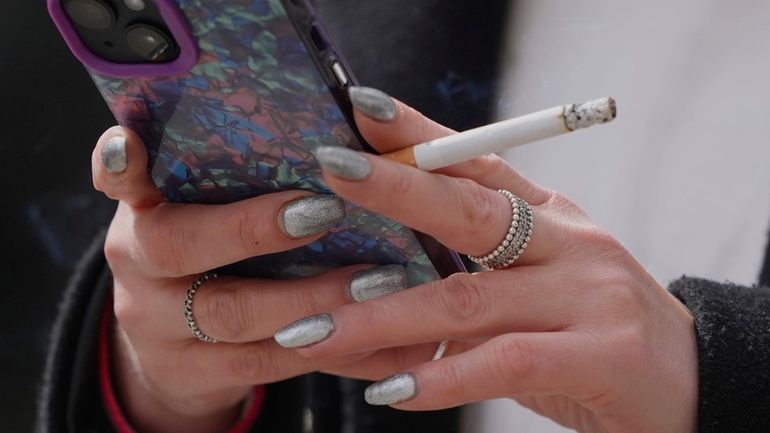 A woman smokes on a street, in London, on April...