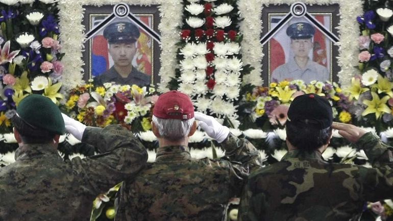 Marine veterans salute Saturday in front of the portraits of...