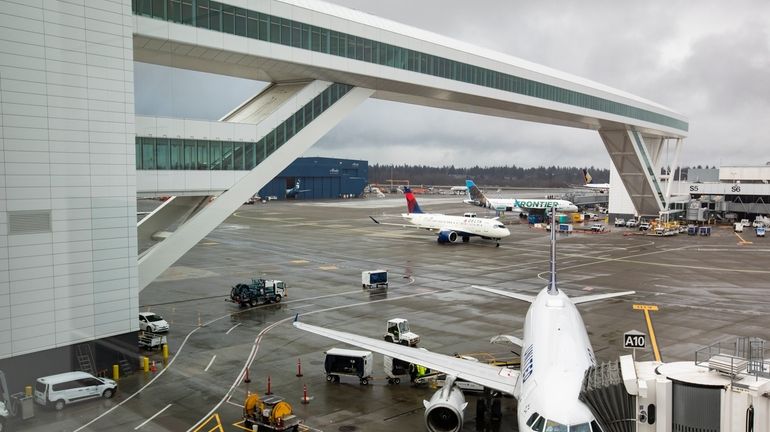 Planes taxi under the aerial passenger walkway at Seattle-Tacoma International...