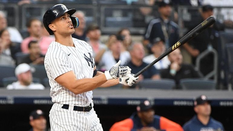 Yankees DH Giancarlo Stanton watches the flight of his three-run...