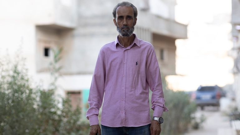 Mohsen al-Sheikh, 52, stands in his neighborhood of the city...