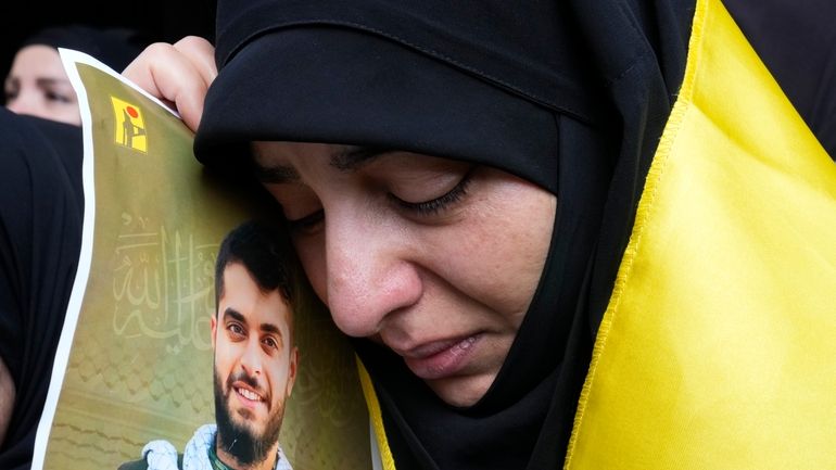 A woman holds a picture of a Hezbollah member who...