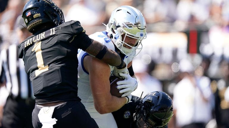 Kentucky tight end Brenden Bates, center, makes a catch past...