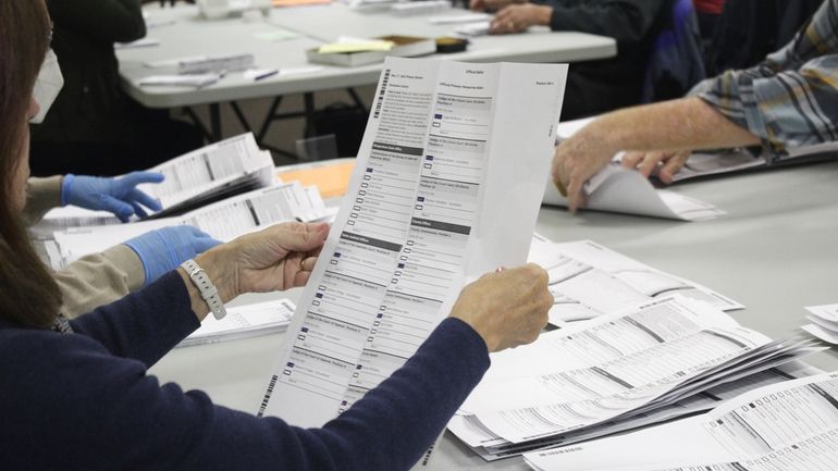 FILE— An election worker examines a ballot at the Clackamas...