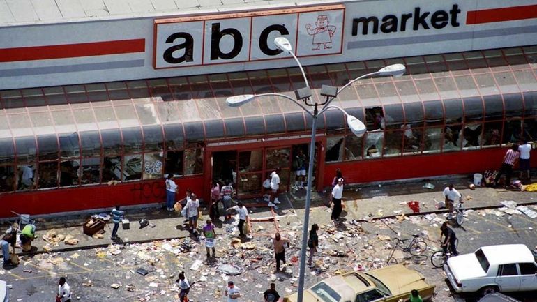 In this April 30, 1992 file photo, looters mill in...