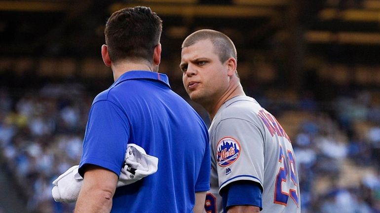 Mets assistant athletic trainer Joseph Golia, left, assists Devin Mesoraco...